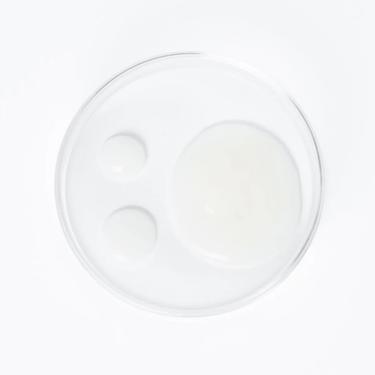 Essence à la vitamine C YOUNIQUE YOU·NIVERSAL : texture de l’essence : coupelle en verre vue du dessus avec un liquide laiteux jaune pâle