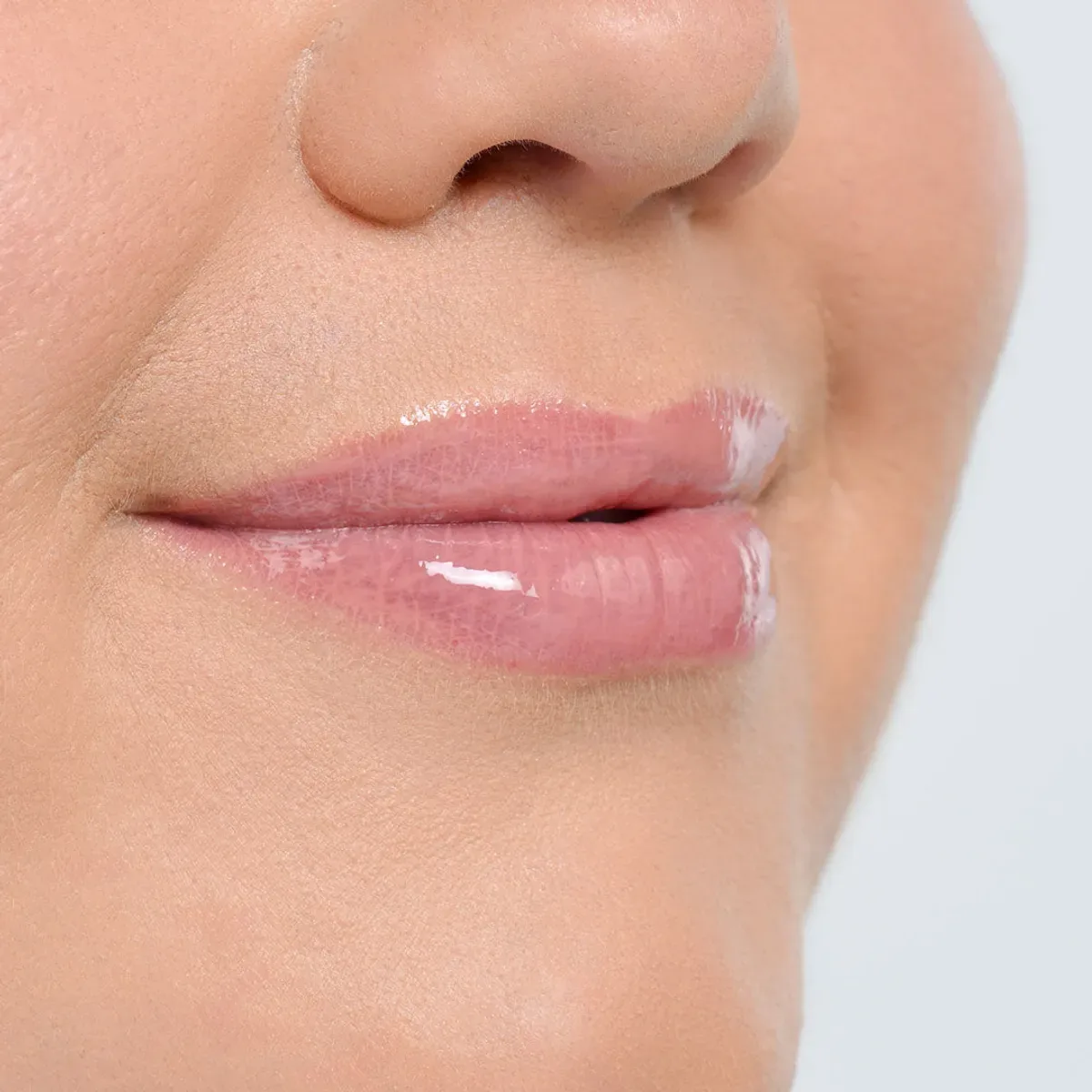 YOUNIQUE BARE·YOU lip balm – where to buy : close-up of closed lips with a glossy translucent pink finish on a soft blue-grey background