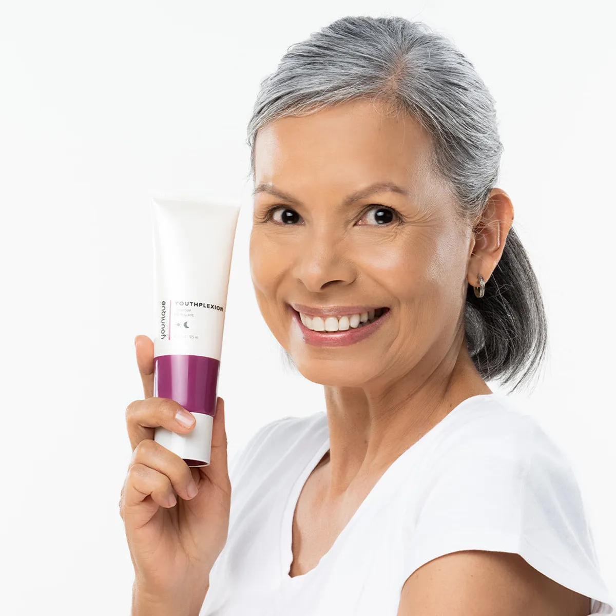 Limpiador YOUTHPLEXION – consejos: mujer madura sujetando el tubo de limpiador facial