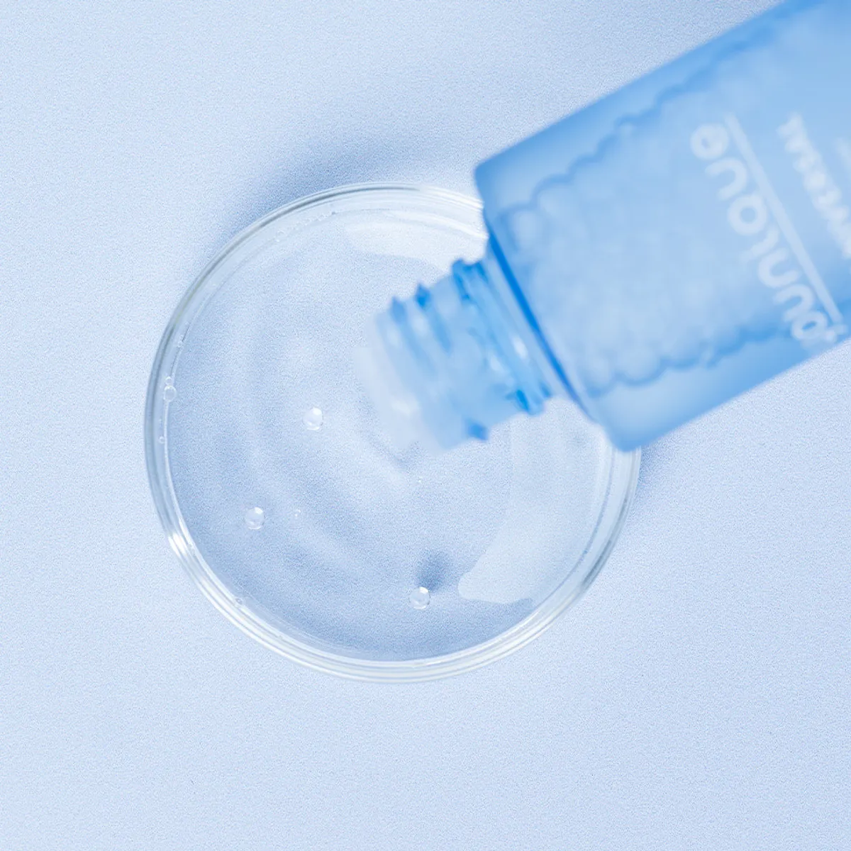 Toner illuminateur YOUNIQUE YOU·NIVERSAL – prix : gros plan du flacon versant le toner transparent dans une coupelle en verre