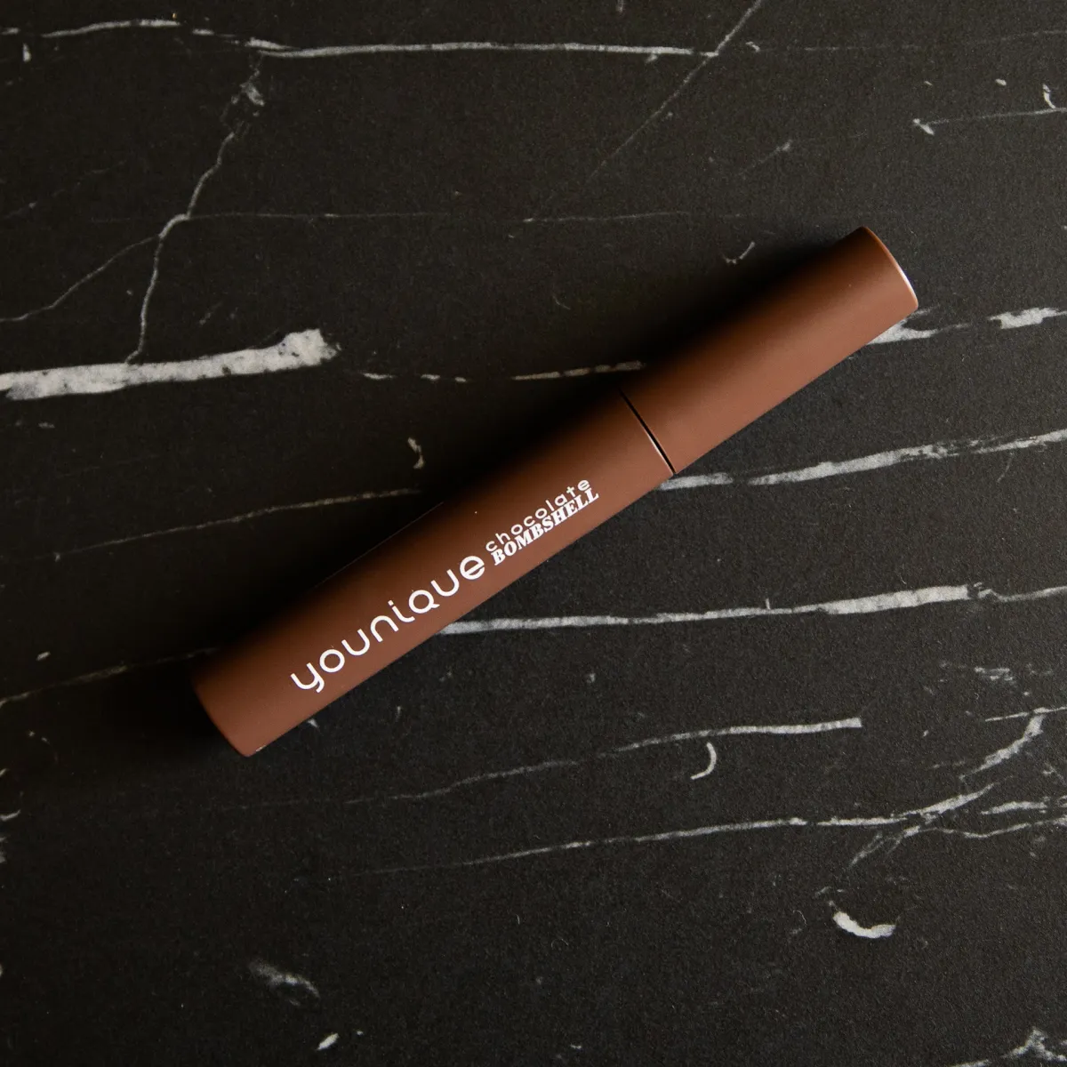 YOUNIQUE chocolate bombshell tubing-mascara – pris : tube med brun mascara på sort marmor