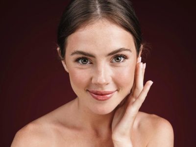 Image of gorgeous happy woman with clean fresh face smiling at camera isolated over red background